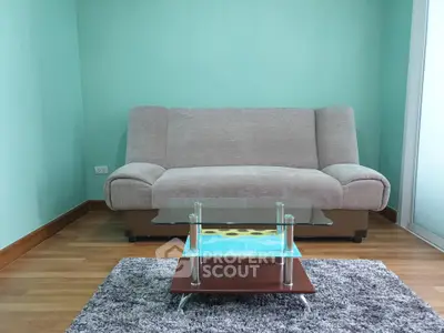 Modern living room with stylish sofa and glass coffee table on a plush rug.