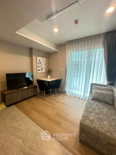 Modern living room with stylish decor, cozy seating, and natural light from large window.