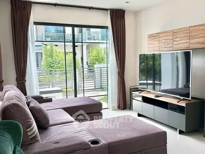Spacious living room with modern decor and garden view, featuring a large TV and comfortable seating.