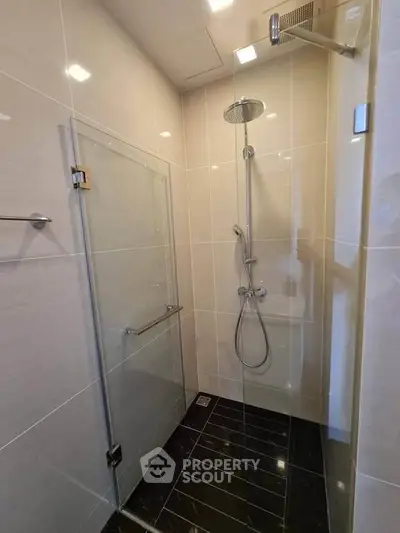 Modern bathroom with sleek glass shower enclosure and rainfall showerhead.