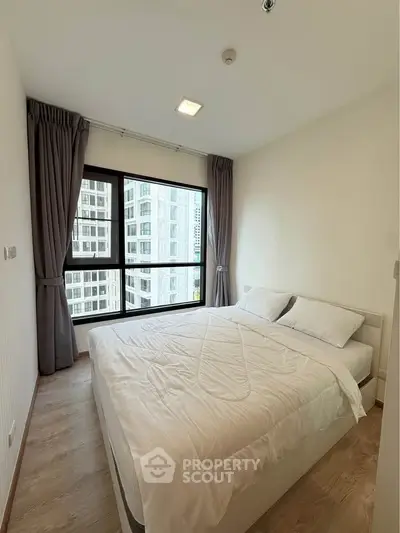 Modern bedroom with large window and city view in high-rise apartment