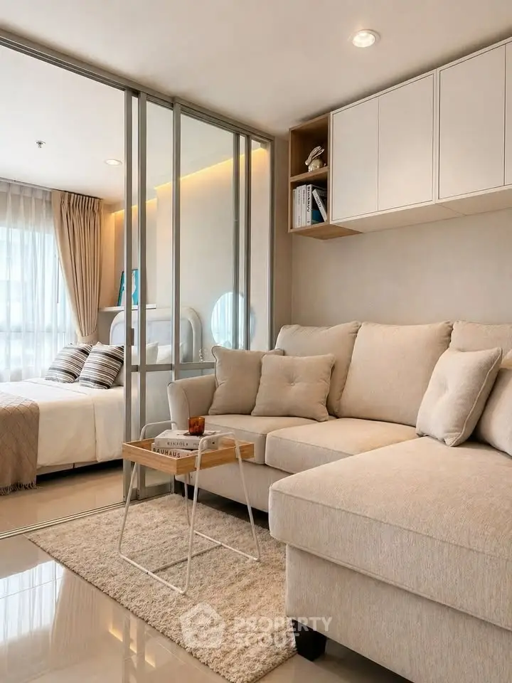 Modern living room with cozy beige sofa and glass partition leading to a stylish bedroom.