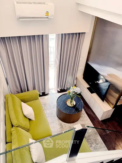 Modern living room with green sofa, TV, and air conditioning in stylish apartment.