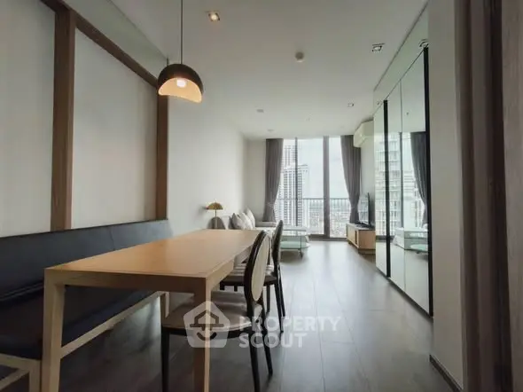 Modern living room with city view, stylish dining area, and floor-to-ceiling windows.