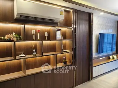 Modern living room with stylish wooden shelving and mounted TV, featuring elegant decor and ambient lighting.