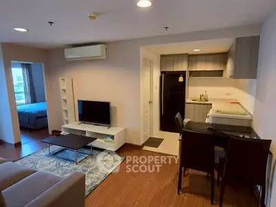 Modern open-plan living room with kitchen and dining area, featuring sleek furniture and warm lighting.