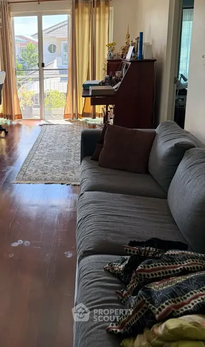 Spacious living room with cozy sofa and natural light from balcony view.
