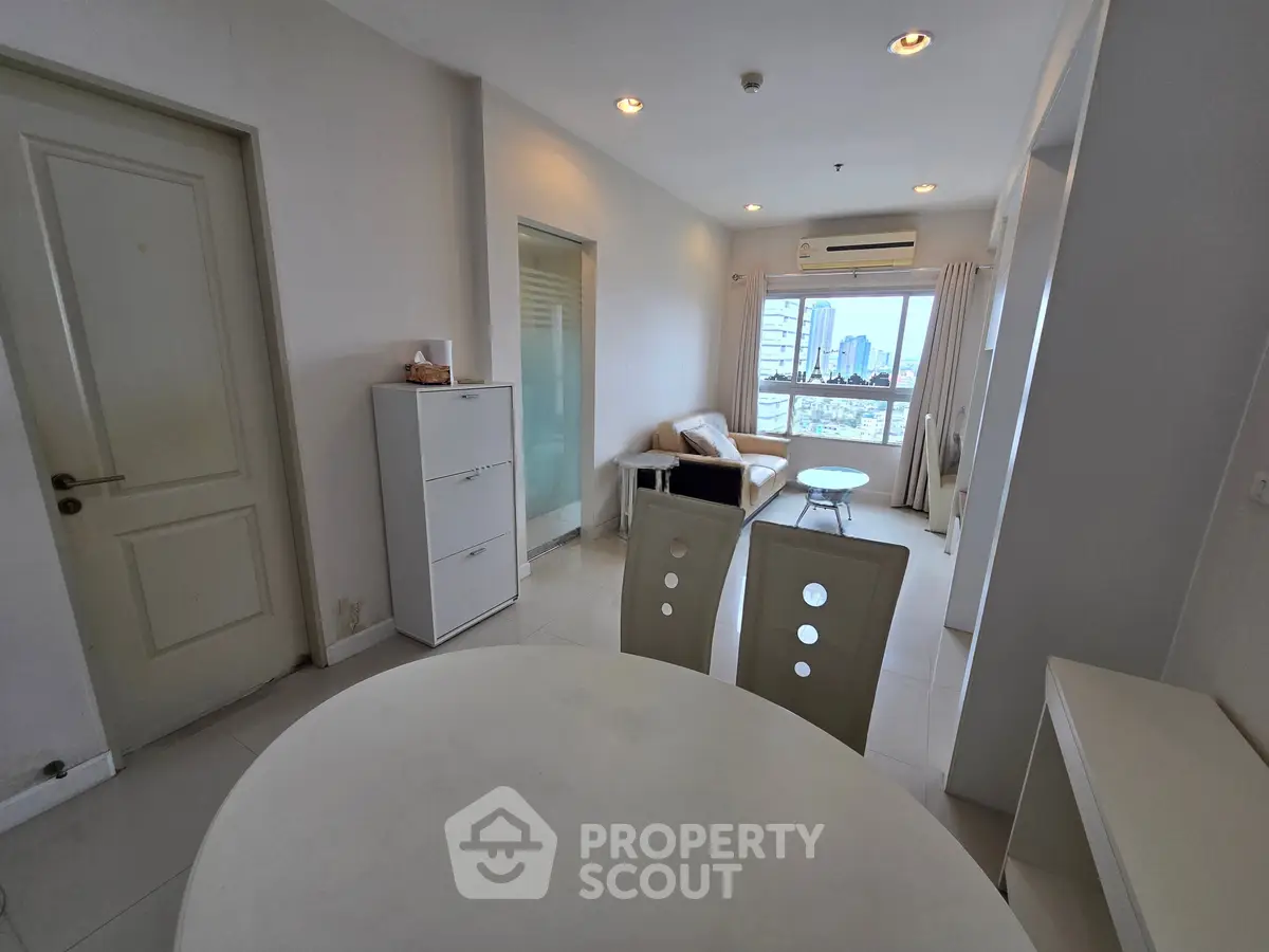 Modern apartment interior with dining area and city view, featuring sleek furniture and neutral tones.