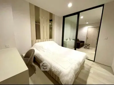 Modern bedroom with elegant decor and large glass partition, featuring a cozy bed and stylish chair.