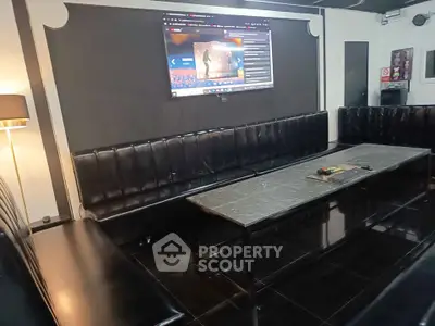Luxurious entertainment room with sleek black leather seating and large screen, perfect for gatherings.