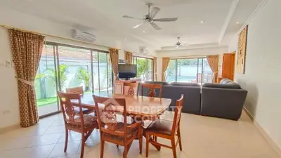Spacious living room with elegant dining set and large windows offering garden views.