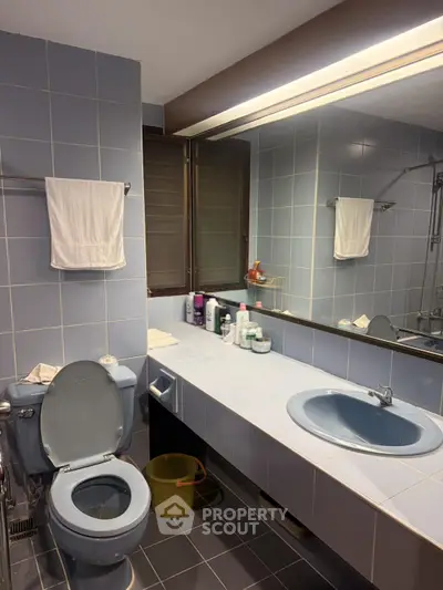 Spacious bathroom with modern fixtures and large mirror in a stylish real estate property.