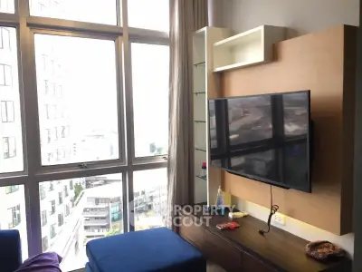 Modern living room with large windows and wall-mounted TV in a high-rise apartment.