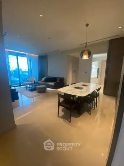 Luxurious open-plan living and dining area with city view, featuring modern furniture and elegant lighting.