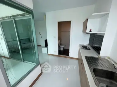 Modern studio apartment with sleek kitchen and glass partitioned bedroom.