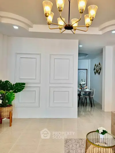 Elegant living room with modern chandelier and stylish dining area, perfect for contemporary living.