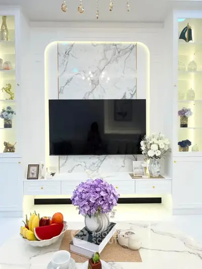 Luxurious living room with marble accents and elegant decor, featuring a large TV and stylish shelving.
