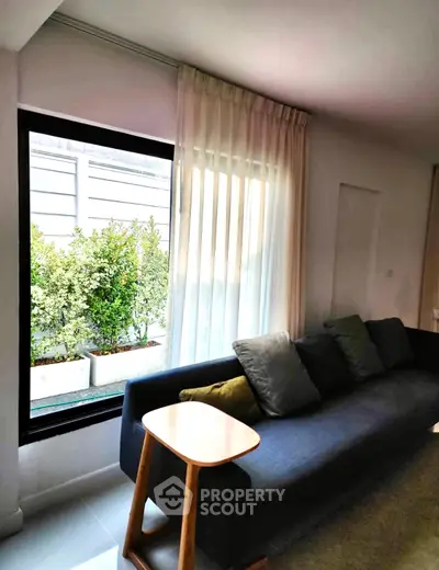 Modern living room with large window and stylish sofa, offering a cozy and inviting atmosphere.