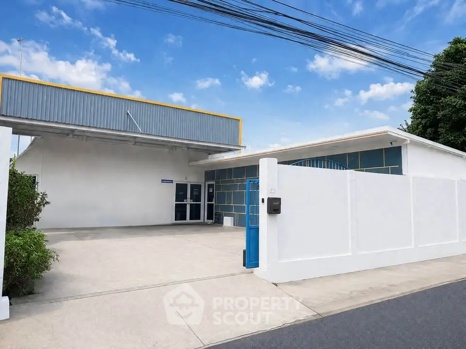 Modern industrial building with spacious driveway and secure gated entrance.