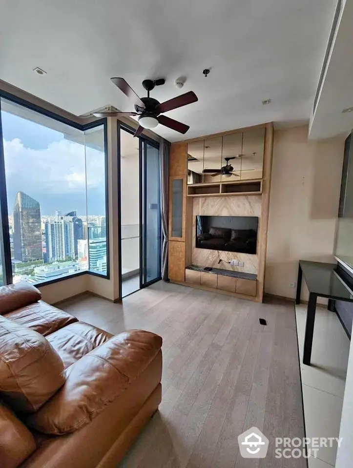 Modern living room with city view, featuring leather sofa and ceiling fan