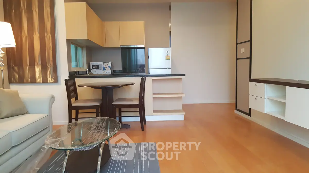 Modern open-layout living room with kitchen, featuring stylish furniture and wooden flooring.