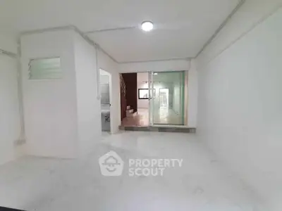 Spacious interior with white walls and marble flooring, featuring a sliding glass door leading to another room.