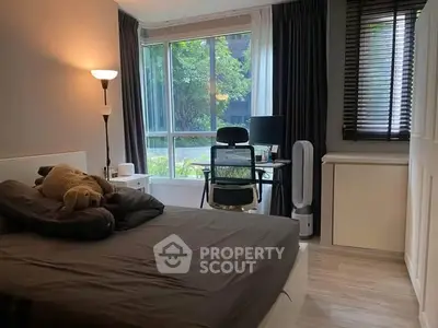 Cozy bedroom with large window and study area, perfect for relaxation and productivity.