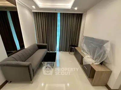 Modern living room with sleek sofa and TV setup, featuring elegant curtains and glossy tiled flooring.