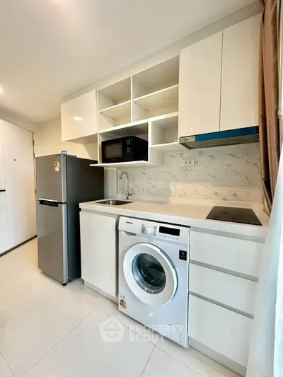 Modern kitchen with sleek appliances and washing machine in compact layout.