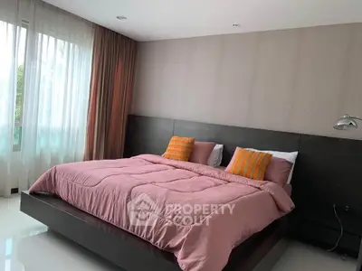 Spacious bedroom with modern decor and large windows for natural light.