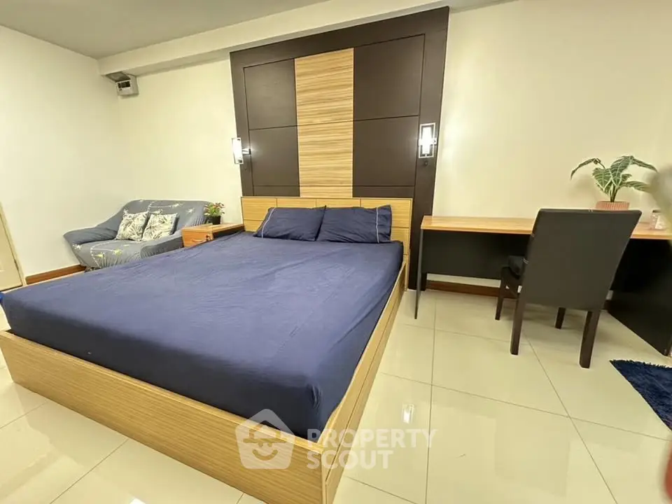 Spacious bedroom with modern design, featuring a comfortable bed, cozy sofa, and a sleek desk area.