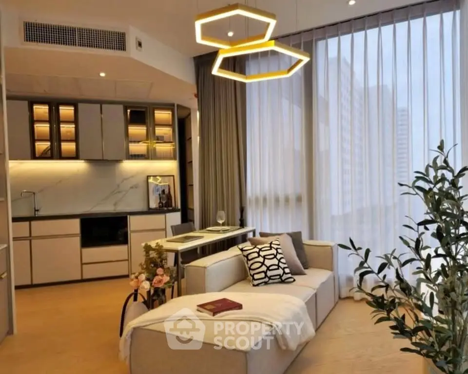 Modern living room with stylish lighting and open kitchen layout, featuring cozy seating and large windows.