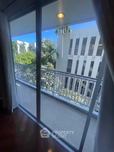 Spacious balcony with stunning view of lush greenery and modern architecture, perfect for relaxation.