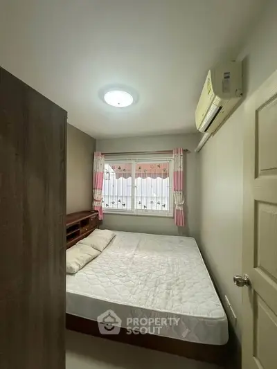 Cozy bedroom with natural light and air conditioning, perfect for restful nights.