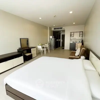 Spacious modern studio apartment with kitchenette and cozy furnishings.