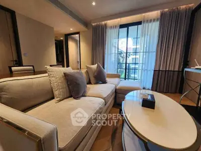Elegant living room with plush sofa and modern decor, featuring large windows and stylish curtains.