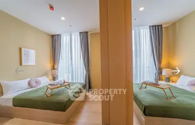 Modern bedroom with twin beds, stylish decor, and natural light from large windows.