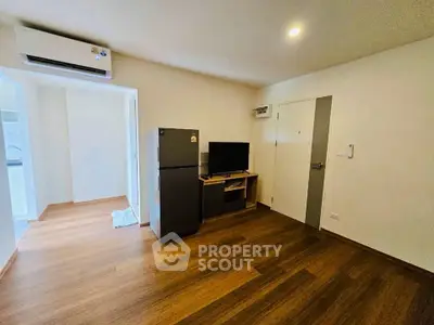Modern living room with wooden flooring, air conditioning, and a sleek TV setup.
