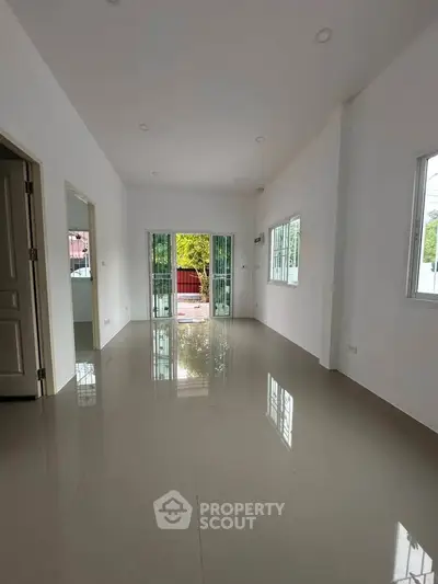 Spacious empty living room with glossy tiled floors and large windows offering natural light.
