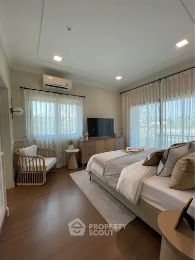 Spacious bedroom with modern decor and large windows offering natural light.