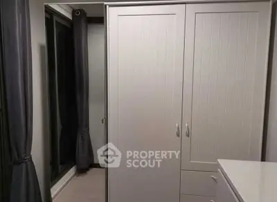 Modern bedroom with sleek wardrobe and large window with curtains.