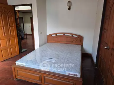 Cozy bedroom with wooden furniture and a comfortable mattress in a well-lit space.