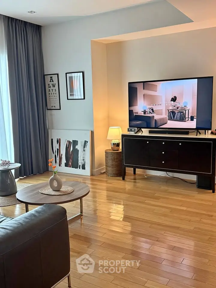 Stylish living room with modern decor, hardwood floors, and large TV for ultimate comfort.