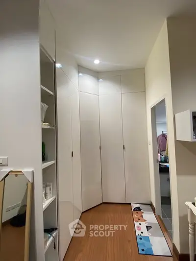 Spacious modern storage area with sleek white cabinets and wooden flooring, perfect for organized living.