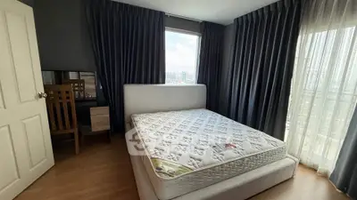 Spacious bedroom with large windows and city view, featuring a comfortable bed and elegant curtains.