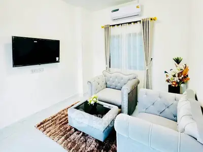 Elegant living room with plush sofas, wall-mounted TV, and air conditioning.