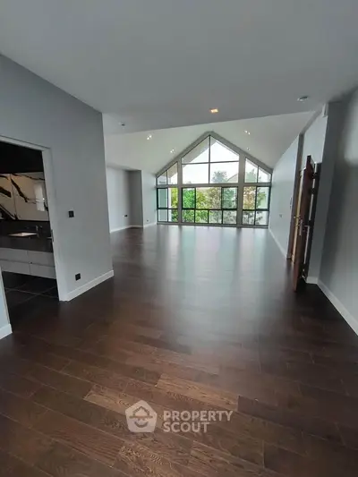 Spacious modern living room with high ceilings and large windows offering natural light and scenic views.