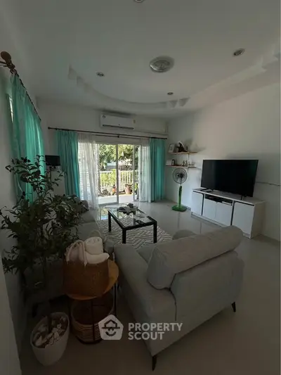 Spacious living room with modern decor and large windows opening to a garden view.