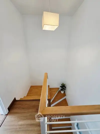 Modern staircase with wooden steps and minimalist decor in a bright home interior.