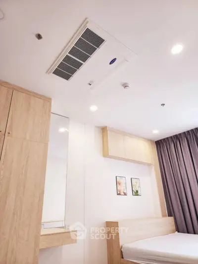 Modern bedroom with built-in wooden furniture and ceiling air conditioning